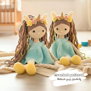 May include: Two handmade crochet dolls with long brown hair, wearing blue dresses and flower crowns. Each doll has yellow crocheted feet and is sitting on a beige blanket. The text "Crochet pattern Unleash your creativity" is at the bottom.