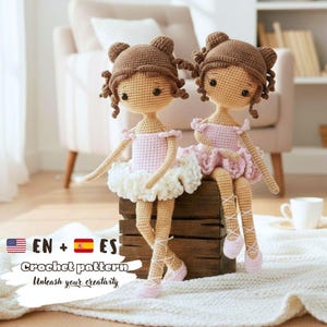 Könnte beinhalten: Zwei handgefertigte gehäkelte Ballerina-Puppen. Jede Puppe hat braunes Haar, das zu Duttfrisuren gestylt ist, und trägt rosa und weiße Tutus und Ballettschuhe. Die Puppen sitzen auf einer Holzkiste. Das Bild enthält den Text "Crochet pattern - Unleash your creativity."