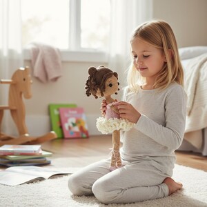Puede incluir: Una mu&ntilde;eca de ganchillo con cabello casta&ntilde;o, un vestido rosa y un tut&uacute; blanco es sostenida por una persona. La mu&ntilde;eca tiene una cara detallada y lleva zapatillas de ballet. El fondo incluye una ventana, un caballito de madera y libros.