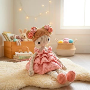 Pu&ograve; includere: Bambola all'uncinetto fatta a mano con testa marrone chiaro e vestito rosa. La bambola ha un copricapo floreale ed &egrave; seduta su un tappeto color crema. Le braccia e le gambe della bambola sono beige chiaro. Un giocattolo fatto a mano affascinante.
