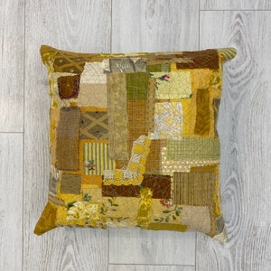 May include: A yellow and brown patchwork cushion cover with a variety of textures and patterns.