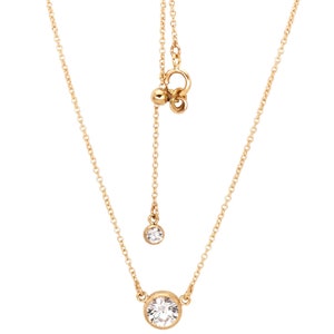 May include: A gold chain necklace with a single round clear stone pendant. The chain has a sliding clasp for adjustable length.