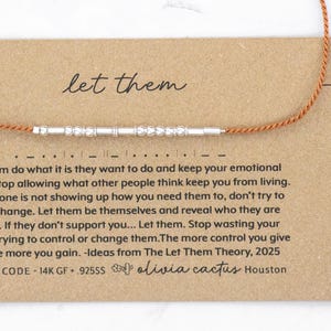 May include: A silver beaded bracelet with a brown cord is displayed on a brown card. The card has the words "let them" in cursive and a message about emotional peace. The bracelet is a Morse code design.