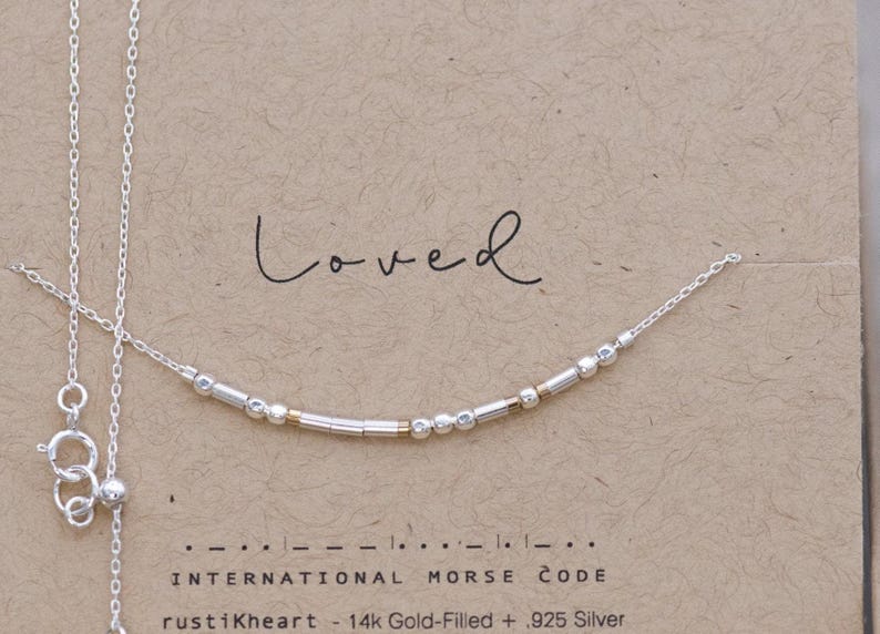 Dainty Silver Chain Loved Morse Code Necklace on a Brown Kraft Card Sowing Morse Code Dots and Dashes Matching the Delicate Chain