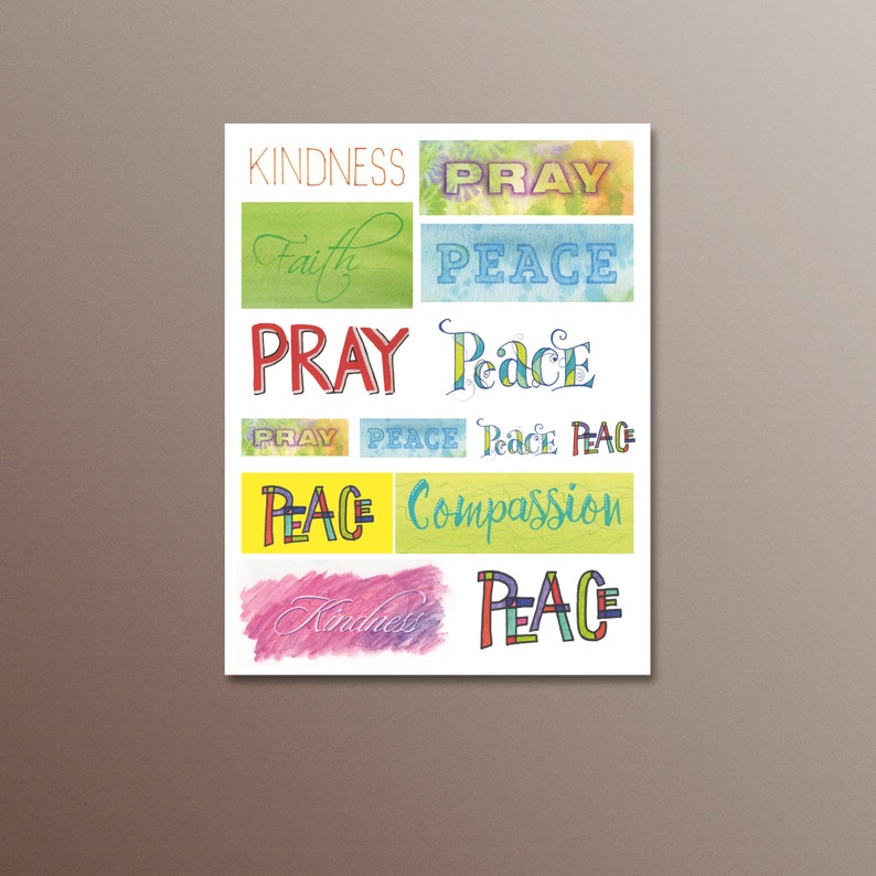 May include: A colourful print featuring the words "kindness", "faith", "pray", "peace", "compassion", and "perce" written in various styles and colours. The words are arranged in a grid pattern on a white background.