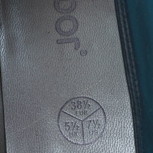 May include: Close-up of the inside of a black shoe with a size chart printed on the insole. The chart shows sizes in US, UK, and EUR. The US size is 7 1/2, the UK size is 5 1/2, and the EUR size is 38 1/2.