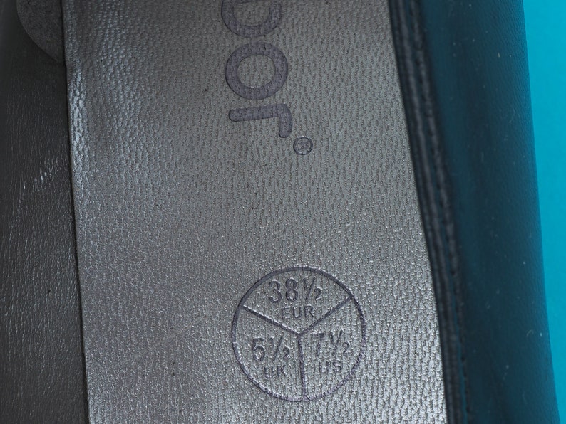 May include: Close-up of the inside of a black shoe with a size chart printed on the insole. The chart shows sizes in US, UK, and EUR. The US size is 7 1/2, the UK size is 5 1/2, and the EUR size is 38 1/2.