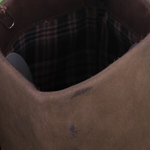 May include: Close-up of the inside of a brown canvas boot with a plaid lining.
