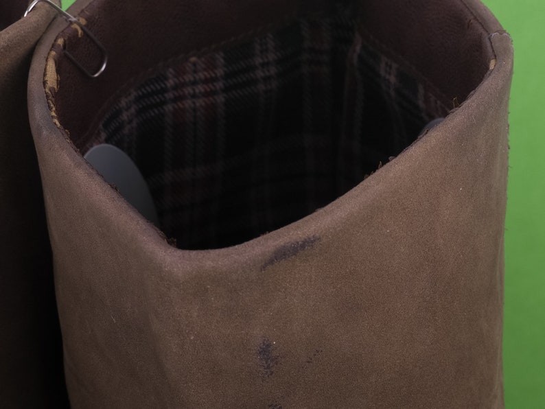 May include: Close-up of the inside of a brown canvas boot with a plaid lining.