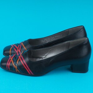 May include: Black leather low heeled shoes with a colorful woven design across the toe.