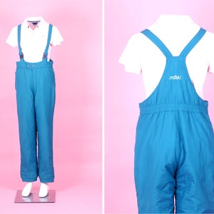May include: Blue ski overalls with adjustable straps and a white "marmot" logo on the back.