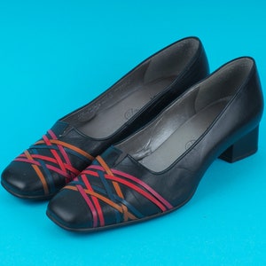 May include: A pair of black leather heeled shoes with a woven design in red, orange, and blue.