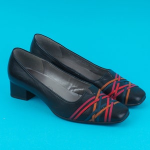 May include: A pair of black leather heeled shoes with a woven design in red, orange, and blue.