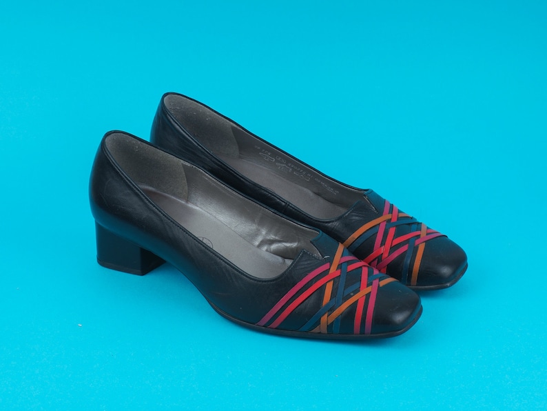 May include: A pair of black leather heeled shoes with a woven design in red, orange, and blue.