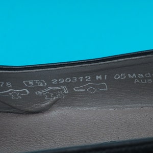 May include: Close-up of the inside of a black leather shoe with the size 5 1/2, 290372 MI 05 Made in Austria printed on the insole.