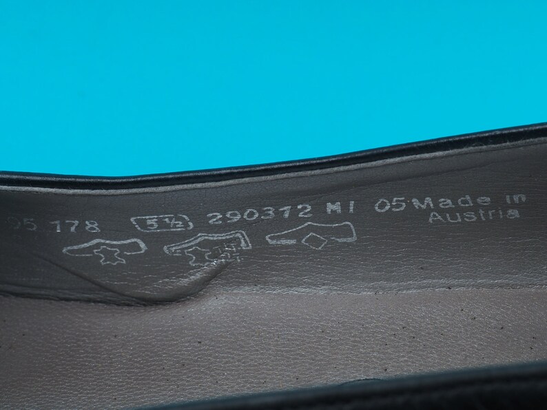 May include: Close-up of the inside of a black leather shoe with the size 5 1/2, 290372 MI 05 Made in Austria printed on the insole.