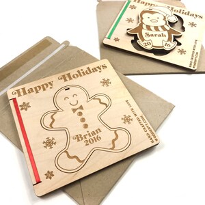 May include: Two wooden Christmas cards with a gingerbread man and a penguin. The gingerbread man card says "Happy Holidays" and "Brian 2016". The penguin card says "Happy Holidays" and "Sarah 2016".