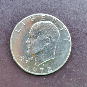 Op de afbeelding: Een zilveren Eisenhower-dollarmunt uit 1972. De munt toont een profiel van een man en de woorden "LIBERTY" en "IN GOD WE TRUST". Het jaartal "1972" is ook zichtbaar.