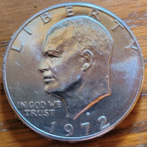 Op de afbeelding: Een zilveren 1972 Eisenhower dollar munt. De munt toont een profiel van president Dwight D. Eisenhower, met de woorden "LIBERTY" en "IN GOD WE TRUST". Het jaartal "1972" is ook zichtbaar.
