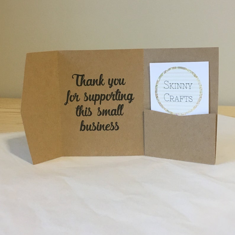 May include: A brown paper thank you card with the text "Thank you for supporting this small business" and a small white card with the text "SKINNY CRAFTS" inside a pocket.