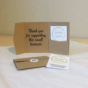 May include: A brown paper thank you card with the text "Thank you for supporting this small business". The card has a pocket on the front with a smaller card inside that says "Skinny Crafts" in a gold circle. The smaller card also has social media information for Skinny Crafts.