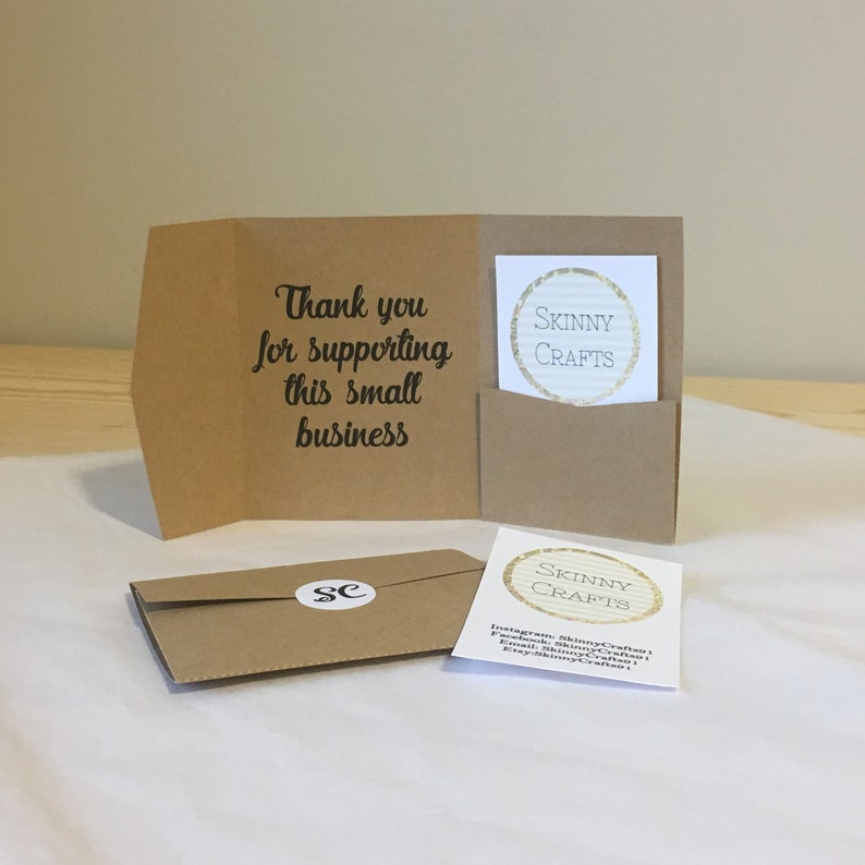 May include: A brown paper thank you card with the text "Thank you for supporting this small business". The card has a pocket on the front with a smaller card inside that says "Skinny Crafts" in a gold circle. The smaller card also has social media information for Skinny Crafts.