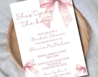 Pode incluir: Um convite de chá de panela branco com laços de aquarela rosa. O texto diz "She's tying the knot!" e inclui detalhes sobre o evento, incluindo o nome da noiva, a data, a hora, o local e as informações de RSVP.
