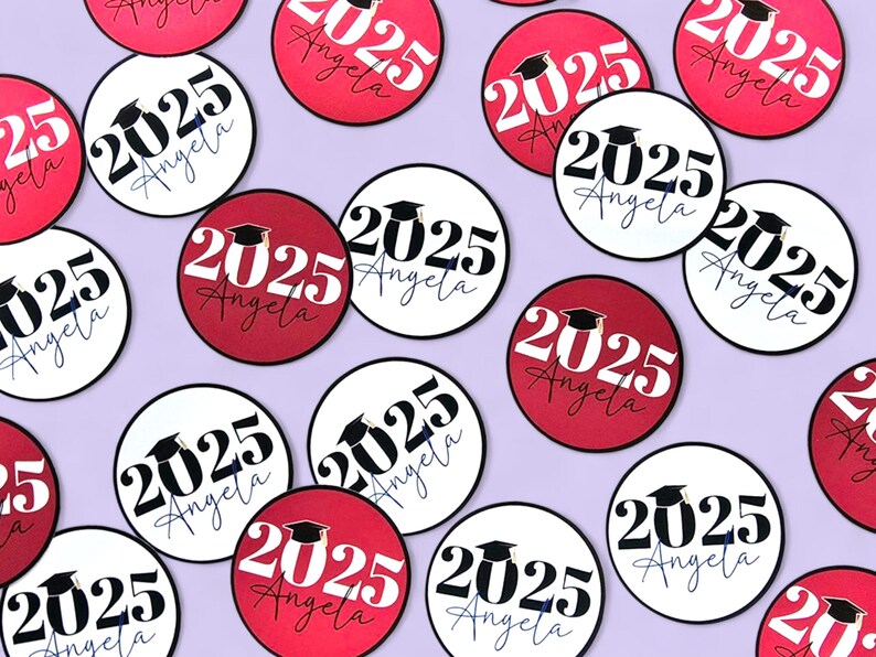 Pode incluir: Autocolantes circulares com o tema da formatura com o texto "2025 Angela" em preto e branco, e vermelho e branco. Uma imagem de um chap&eacute;u de formatura est&aacute; inclu&iacute;da. Os autocolantes est&atilde;o espalhados num fundo lil&aacute;s claro.