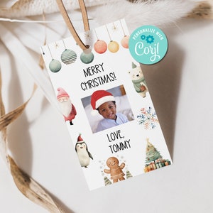 May include: A white Christmas gift tag with a brown leather string. The tag features the text "MERRY CHRISTMAS!" and a photo of a child wearing a Santa hat. Decorative illustrations include a Santa, penguin, and gingerbread man.