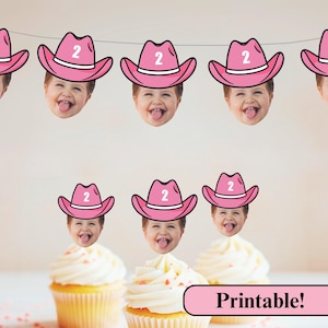 Puede incluir: Una pancarta festiva y adornos para cupcakes con la cara de un niño con un sombrero de vaquero rosa con el número 2. Las magdalenas tienen glaseado blanco. La imagen incluye el texto "Printable!"