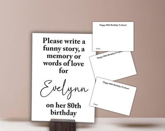 May include: A white card with black text that reads "Please write a funny story, a memory or words of love for Evelynn on her 80th birthday". There are three smaller white cards with black text that reads "Happy 80th Birthday Evelynn!" and "Love".