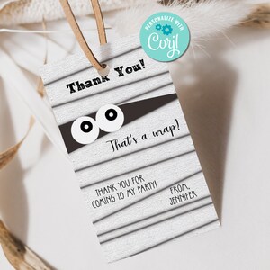 May include: A white thank you tag with a black and white mummy design. The tag says "Thank You! That's a wrap! Thank you for coming to my party! From, Jennifer".