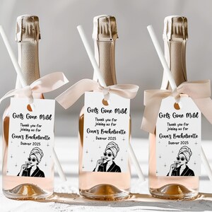 May include: Three champagne bottles with gold foil tops, each adorned with a white tag and a light pink ribbon. The tags read "Girls Gone Mild" and "Gina's Bachelorette Denver 2025". Each bottle has a white straw.
