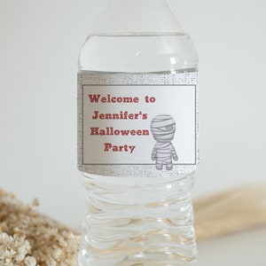 May include: A white water bottle with a label that says "Welcome to Jennifer's Halloween Party". A cartoon mummy is on the label.