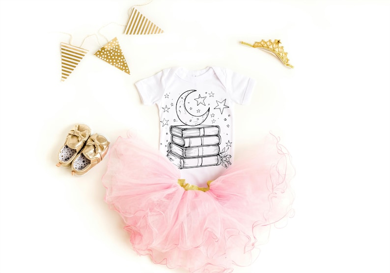 May include: A white baby onesie with a black and white illustration of a crescent moon and stars on top of a stack of books. The onesie is paired with a pink tulle tutu.
