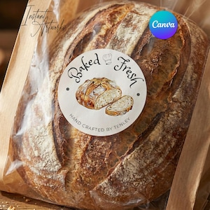 Puede incluir: Una hogaza de pan recién horneado en una bolsa de plástico transparente con un respaldo de papel marrón. Una pegatina redonda en la bolsa dice "Baked Fresh" con una ilustración de acuarela de pan. El texto "Hand Crafted by Tenley" también está en la pegatina.