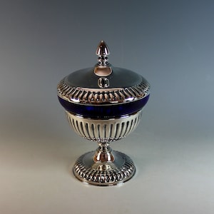 May include: A silver sugar bowl with a blue glass liner and a fluted design. The bowl has a lid with a finial on top.
