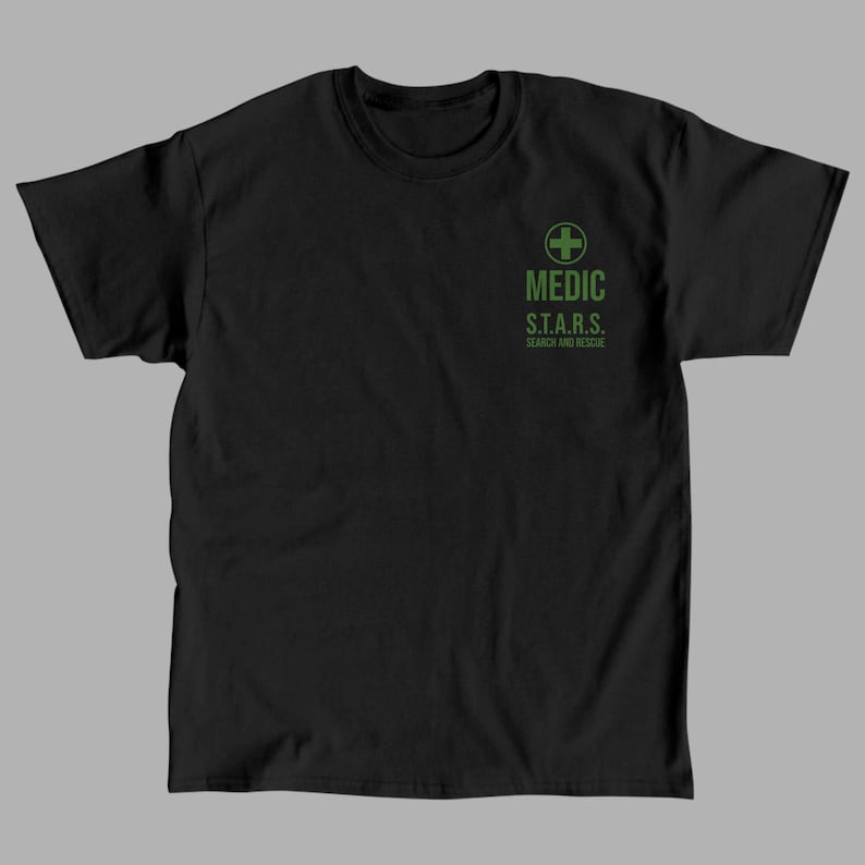 K&ouml;nnte beinhalten: Schwarzes T-Shirt mit einem gr&uuml;nen medizinischen Kreuz und dem Text "MEDIC S.T.A.R.S. SEARCH AND RESCUE"