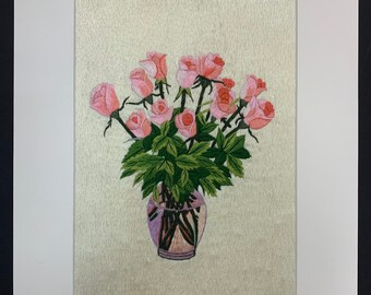 Pode incluir: Um bordado emoldurado de um buquê de rosas cor-de-rosa em um vaso com folhas verdes. As rosas estão dispostas em um cacho e o vaso é decorado com um padrão preto e branco.
