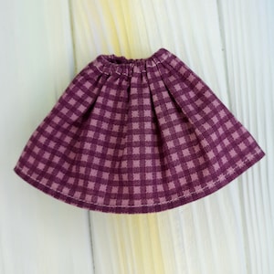 Könnte beinhalten: Ein lila-weiß karierter Rock mit einem gerafften Bund.