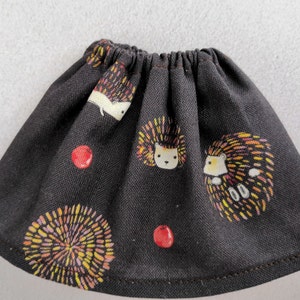 Puede incluir: Una falda negra con estampado de erizos y bayas. La falda est&aacute; hecha de una tela de algod&oacute;n suave y tiene una cintura el&aacute;stica.