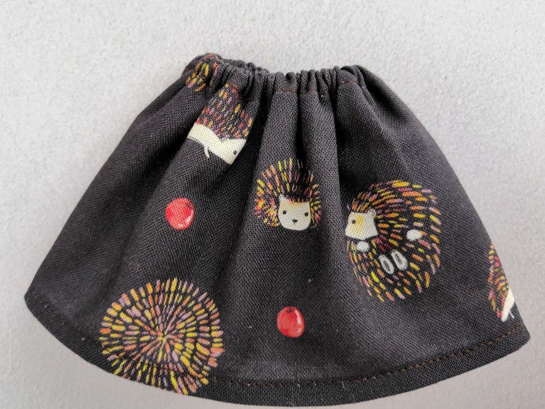 Puede incluir: Una falda negra con estampado de erizos y bayas. La falda est&aacute; hecha de una tela de algod&oacute;n suave y tiene una cintura el&aacute;stica.