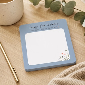 May include: A square notepad with a dusty blue border and a white center. The top of the border features the text "Today's plan is simple: PANIC QUIETLY AND HOPE FOR THE BEST." The bottom right corner of the white area has a small floral illustration.