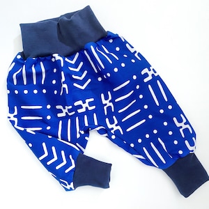 May include: Blue and white patterned baby pants with navy blue cuffs. The pants have a geometric pattern.