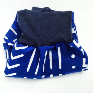 May include: Blue and white patterned fabric with a navy blue fold-over waistband. The fabric has a geometric pattern of white lines and dots on a blue background.