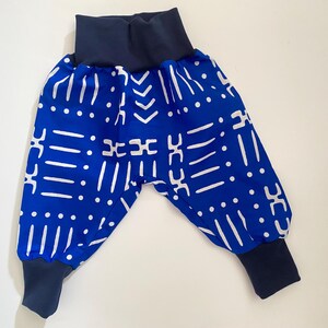 May include: Blue and white patterned baby pants with a navy blue elastic waistband and cuffs.