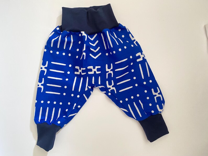 May include: Blue and white patterned baby pants with a navy blue elastic waistband and cuffs.