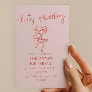 Puede incluir: Una invitación de cumpleaños rosa con texto rojo y una ilustración de copa de champán. La invitación dice "thirty something" e invita a los invitados a celebrar el cumpleaños de Adrianne el 15 de noviembre a las 6:30 PM.