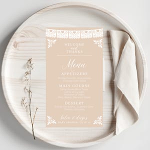 May include: A light brown menu card with white text and a decorative border. The menu includes appetizers, main course, and dessert options. The text at the bottom reads "belen & diego's baby shower july 10".
