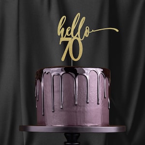 May include: A purple cake with chocolate ganache dripping down the sides. The cake is topped with a gold glitter cake topper that says "hello 70".